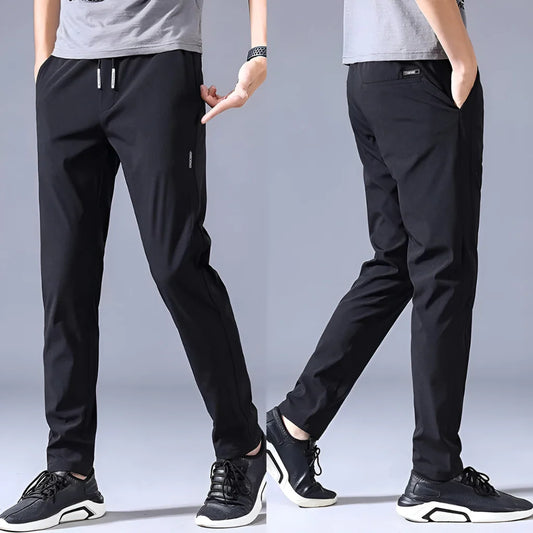 Two pairs of black pants worn by models on a gray background